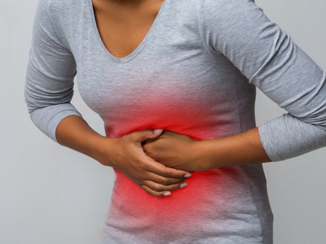 Woman with abdominal pain over grey background