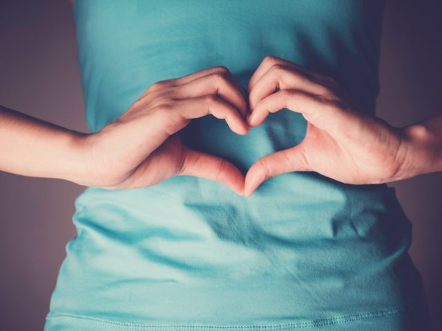 Woman hands making a heart shape on her stomach, healthy bowel degestion, probiotics for gut health