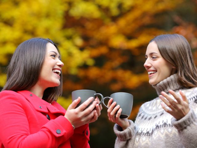 Happy friends talking with coffee mugs in a park