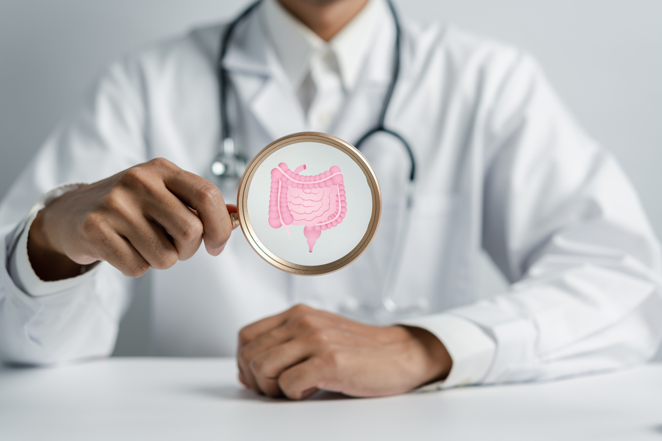 Doctor holding Magnifier focus to stomach with intestine virtual icon, probiotics food for gut health, intestine cancer, bowel inflammatory. Healthy care concept.